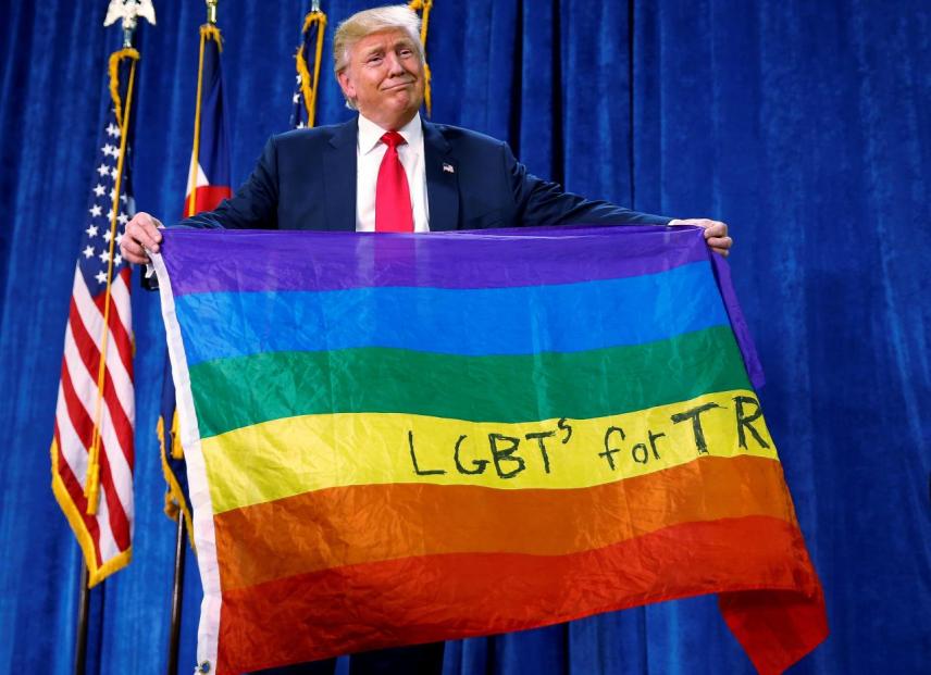 Donald Trump holds up a rainbow flag with "LGBTs for TRUMP" written on it at a campaign rally in Greeley, Colorado, U.S. October 30, 2016. REUTERS/Carlo Allegri